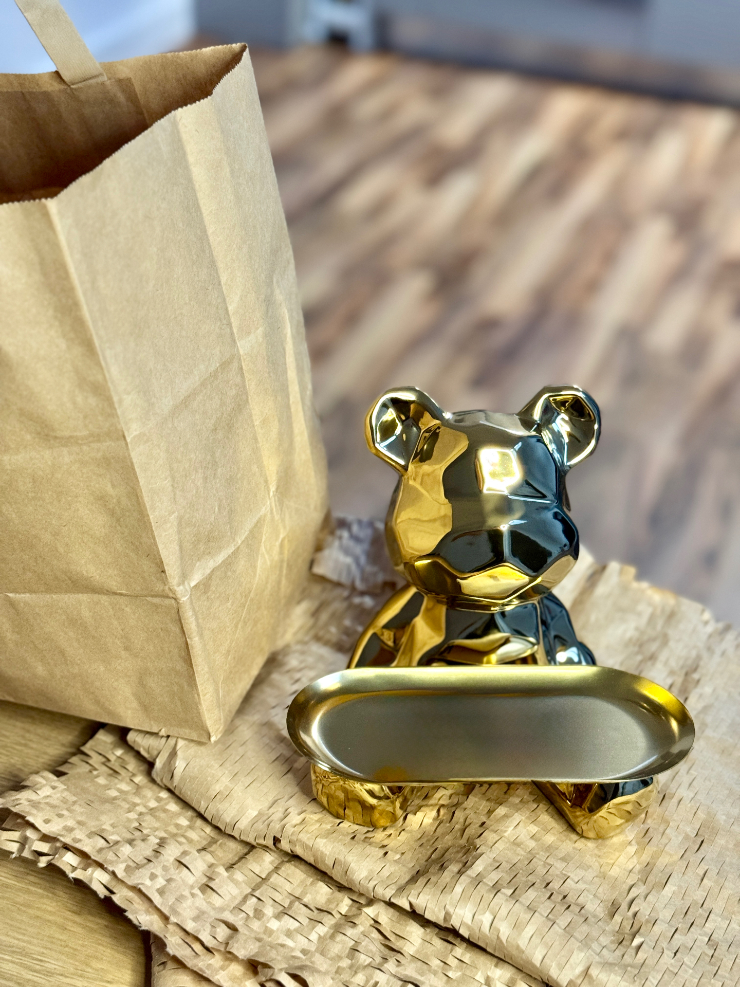 Figurina MoneyBear aurie lângă o pungă cadou